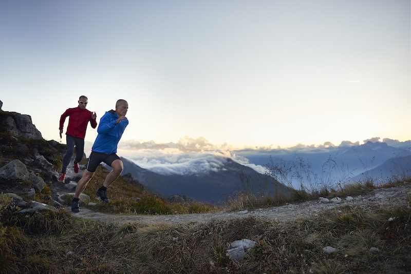 Mannen lopen op pad in de bergen - trailrunning